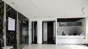 A modern hotel lobby with a reception desk, a glass partition, and a marble wall. - Jinjiang Inn Zhuji Datang Hotel (Shaoxing)