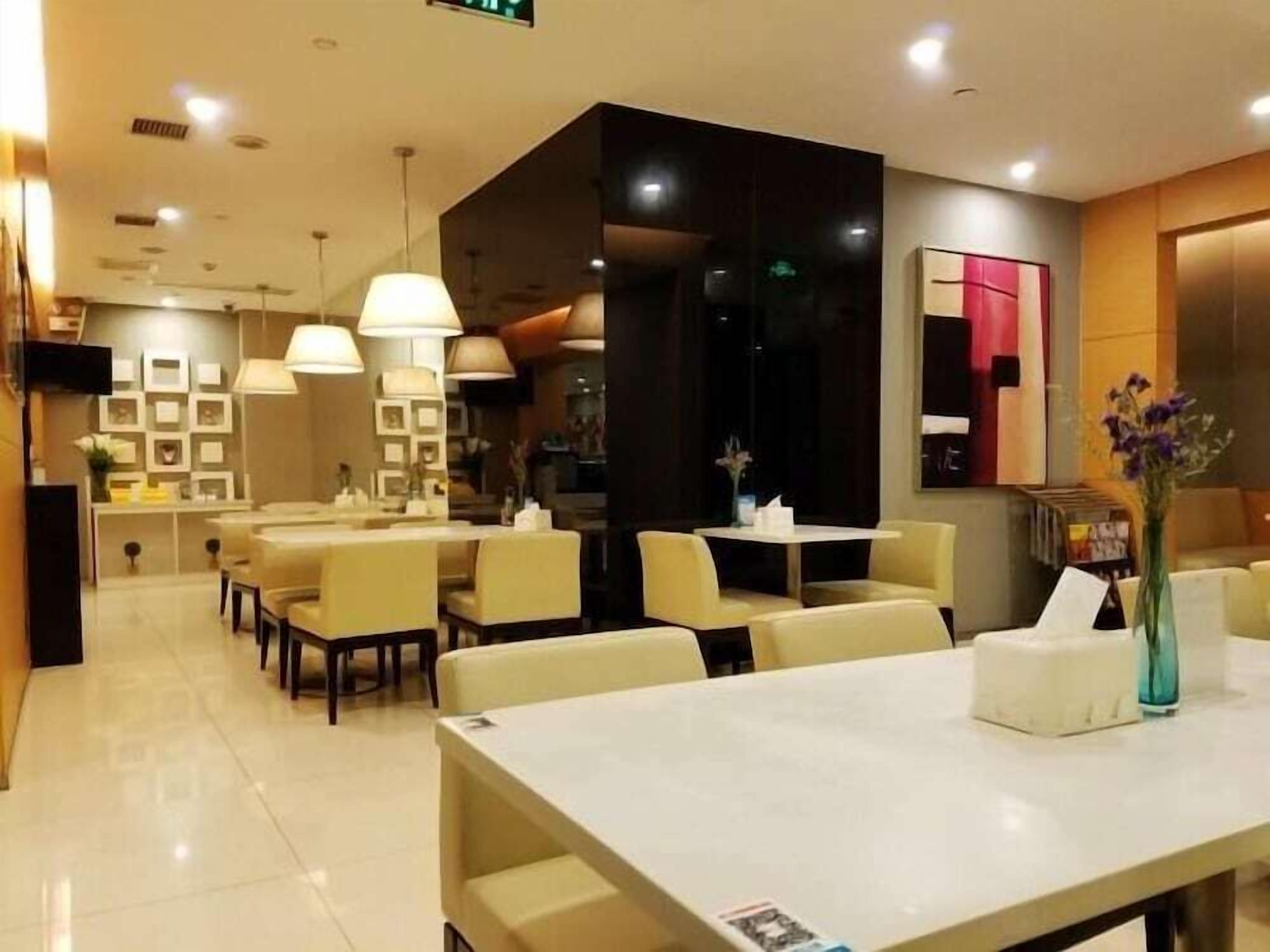 Un restaurante moderno con varias mesas y sillas, una barra y luminarias colgantes.