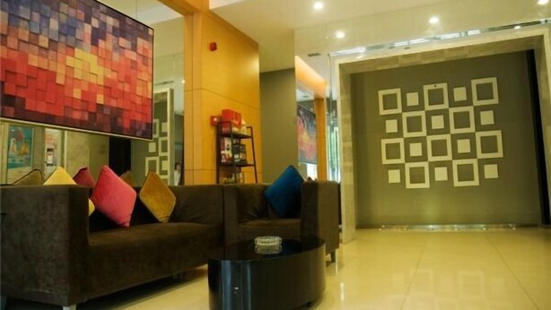 A modern lobby with a dark brown sofa, a glass coffee table, and a colorful abstract wall. - Jinjiang Inn Chuzhou Langya Street (Chuzhou)