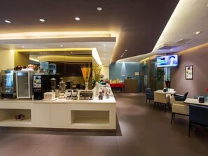 Eine moderne Hotellobby mit einer Rezeption, einer Sitzecke und einem Fernsehbildschirm.