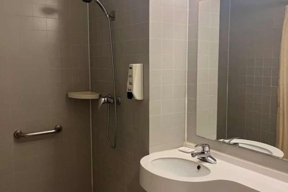 Ein Badezimmer mit Dusche, Waschbecken, Spiegel und Seifenspender.
