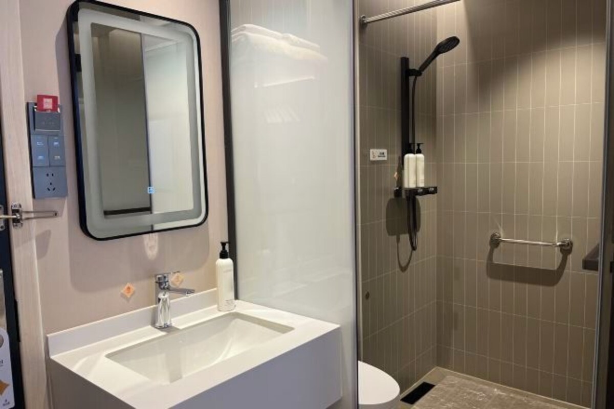 Un baño con lavamanos, espejo y ducha.