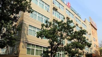A multi-story building with a beige facade, large windows, and a visible logo on the top.