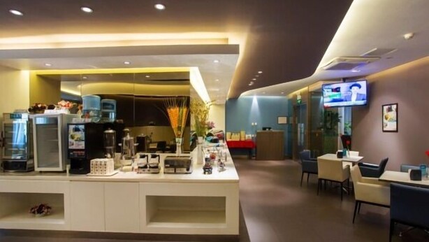 Un hall d’hôtel moderne avec un comptoir d’accueil, un espace salon et un écran de télévision.