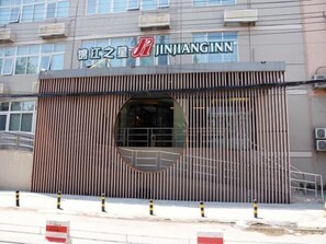 Un edificio con fachada moderna, destacando una entrada principal con un amplio ventanal y una puerta metálica.