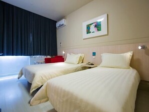 A hotel room with two beds, a red chair, a painting on the wall, and an air conditioning unit.