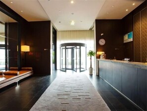 Un hall d’hôtel comprenant un comptoir d’accueil, un espace salon et une porte tournante.