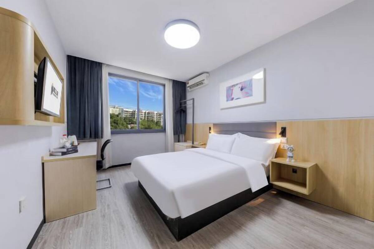 Une chambre d’hôtel moderne, dotée d’un grand lit, d’une table de chevet et d’un bureau avec une chaise.