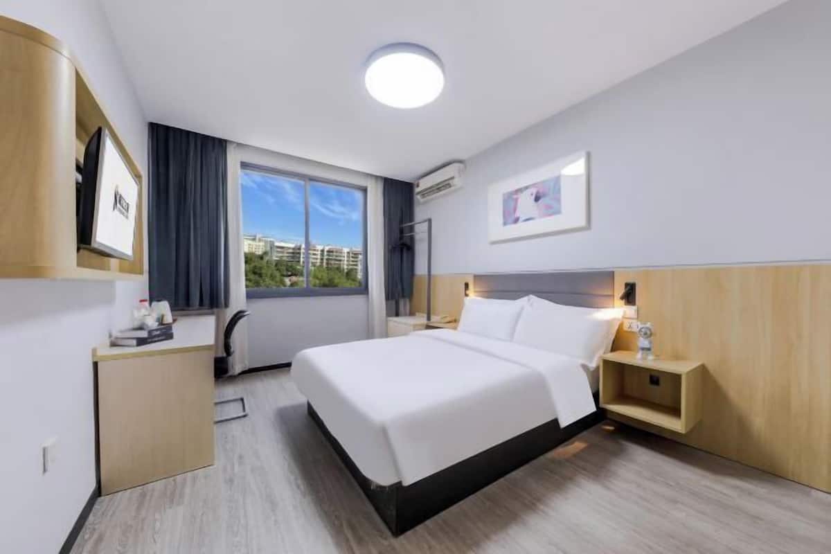 Une chambre d’hôtel comprenant un lit, des tables de chevet, un bureau, une chaise, une fenêtre avec vue et un luminaire au plafond.