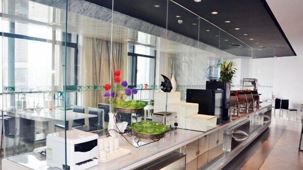 Een moderne hotel lobby met een lange receptiebalie, glazen scheidingswanden en een groot raam dat voor natuurlijk licht zorgt.