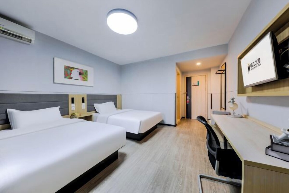 A hotel room with two beds, a desk, and a chair.