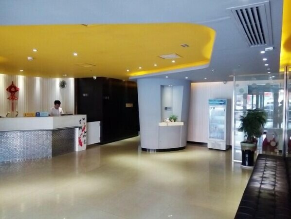 Una moderna zona de recepción de hotel con un mostrador curvo, un recepcionista y una división de vidrio.