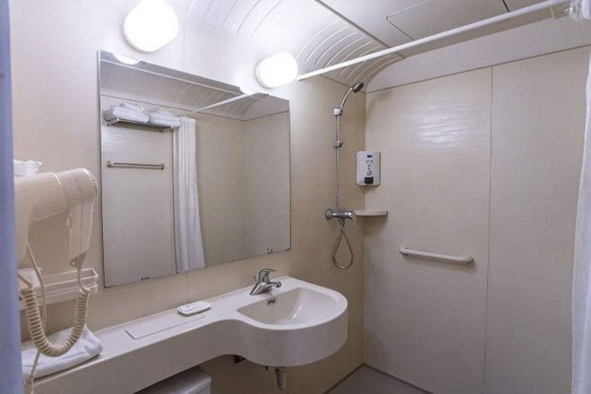 A bathroom with a sink, mirror, towel rack, shower, and a hairdryer.