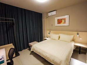 A hotel room with a bed, bedside tables, a desk, a chair, a curtain, and a painting on the wall. - Jinjiang Inn Liuzhou Railway Station North (Liuzhou)
