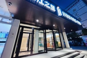A hotel entrance with glass doors, a dark facade, and illuminated signage. - Jinjiang Inn (Ji'nan Qianfoshan Shidong Road Metro Station Hotel) (Jinan)