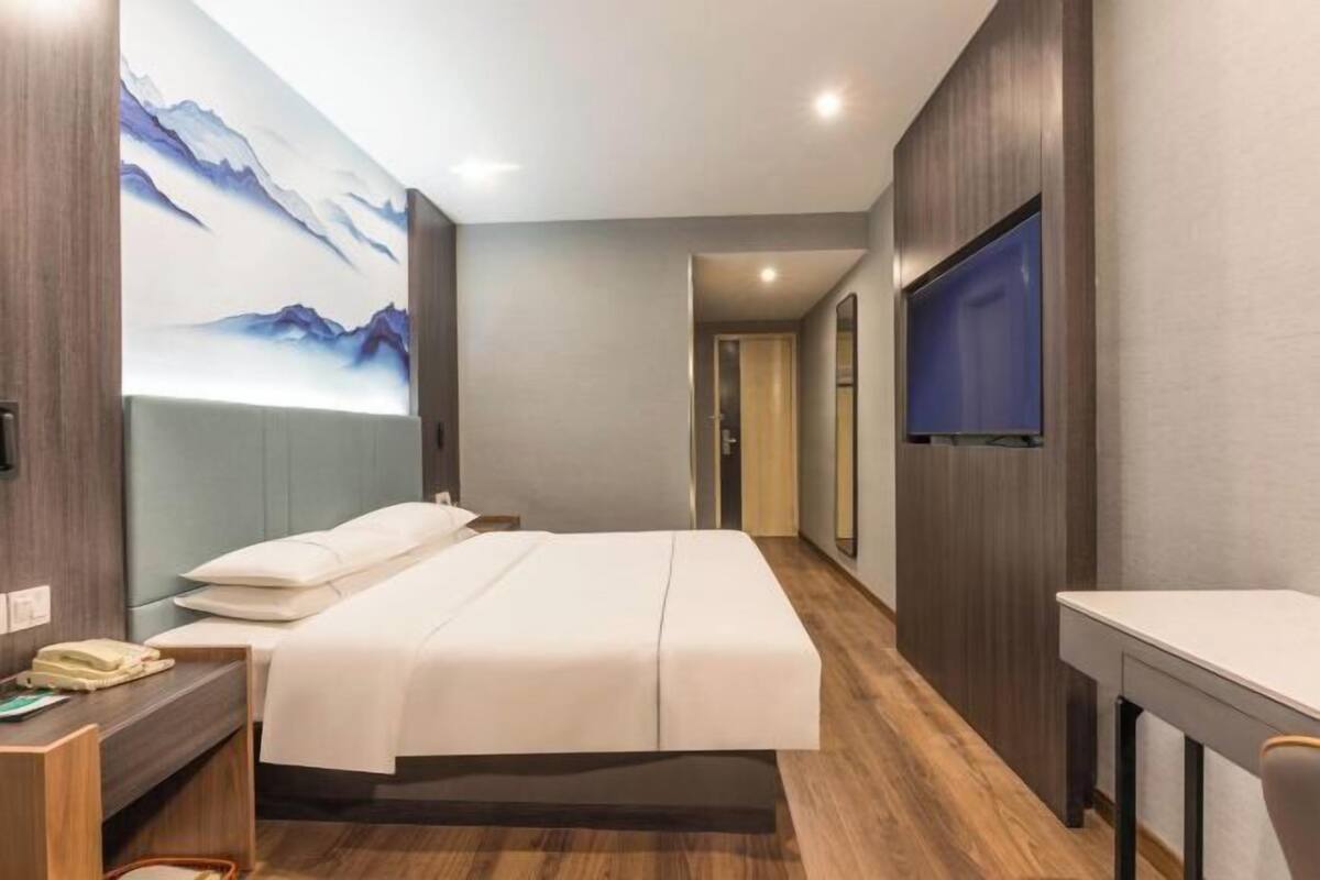 Et hotelværelse med en seng, et sengebord og et fjernsyn.