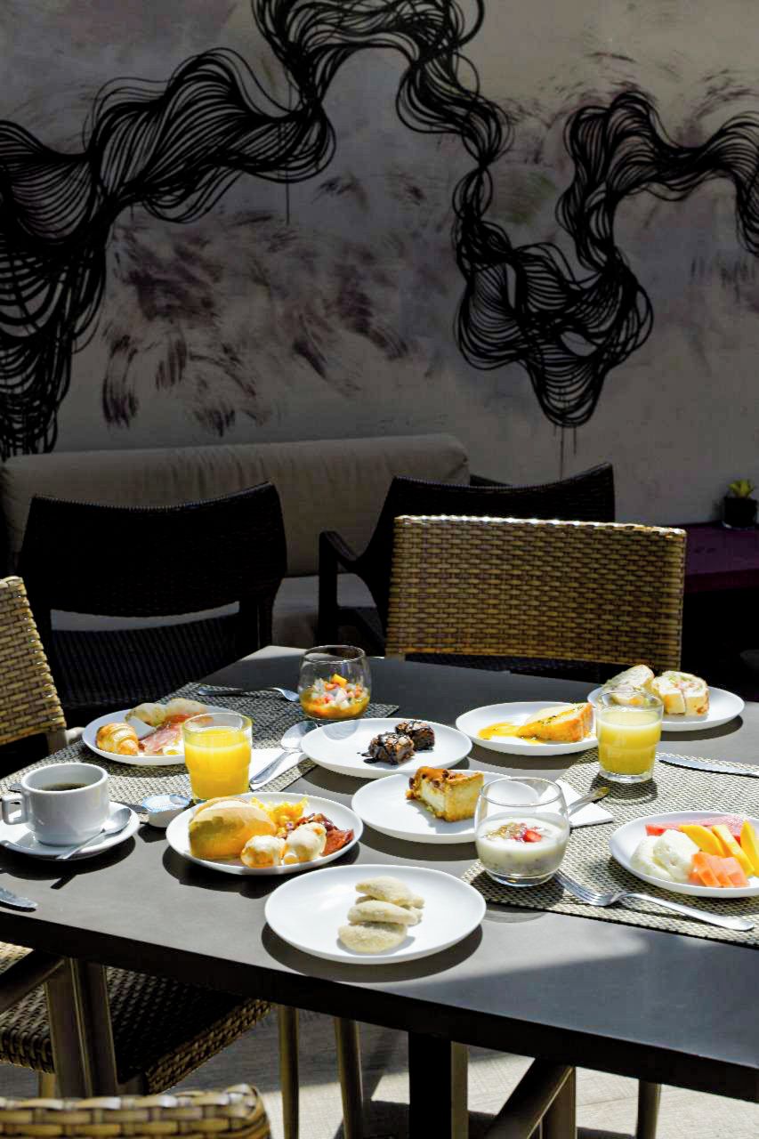 A breakfast table with plates of food, glasses of orange juice, and a cup of coffee.