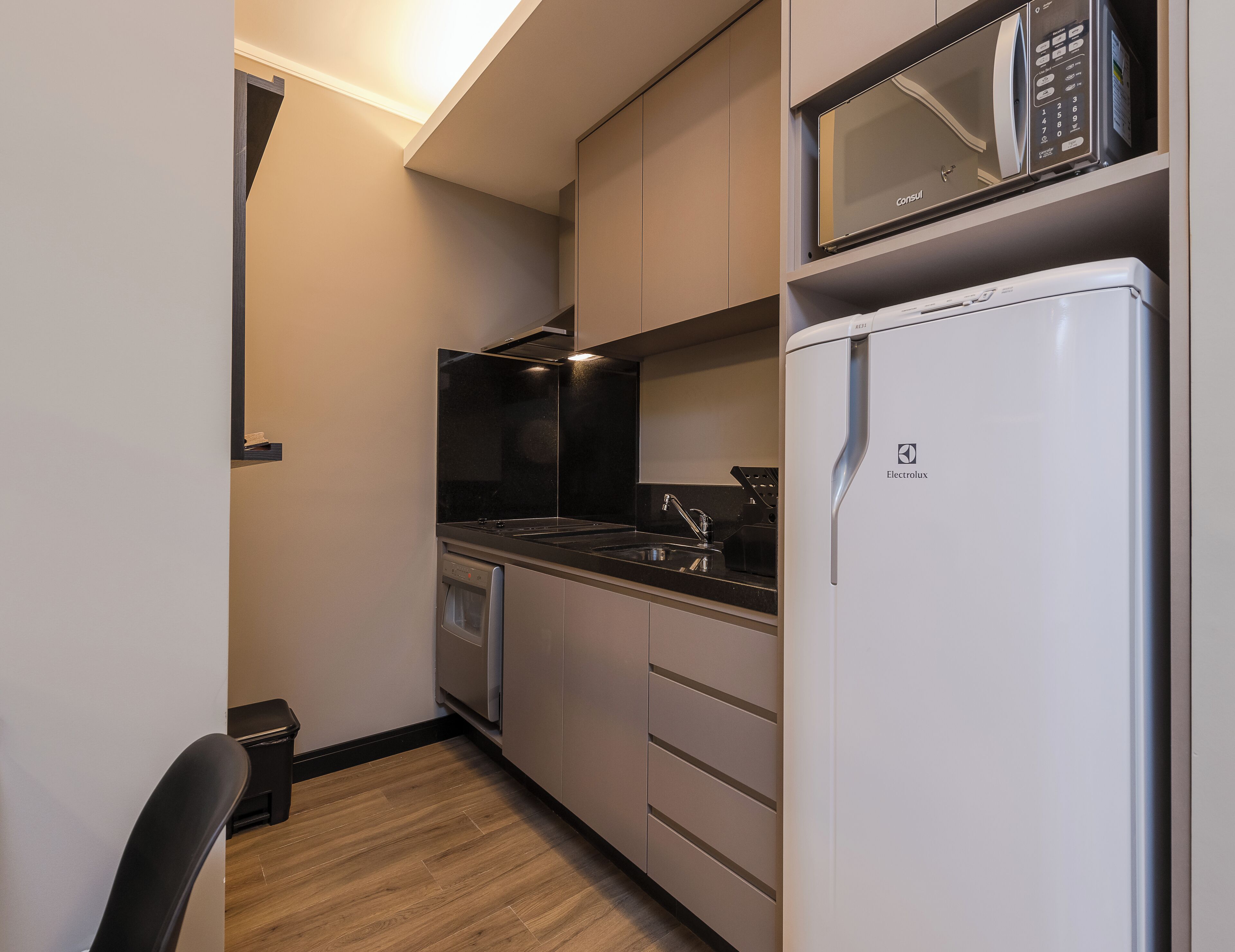 Eine kleine Küchenzeile mit Mikrowelle, Backofen und Kühlschrank.