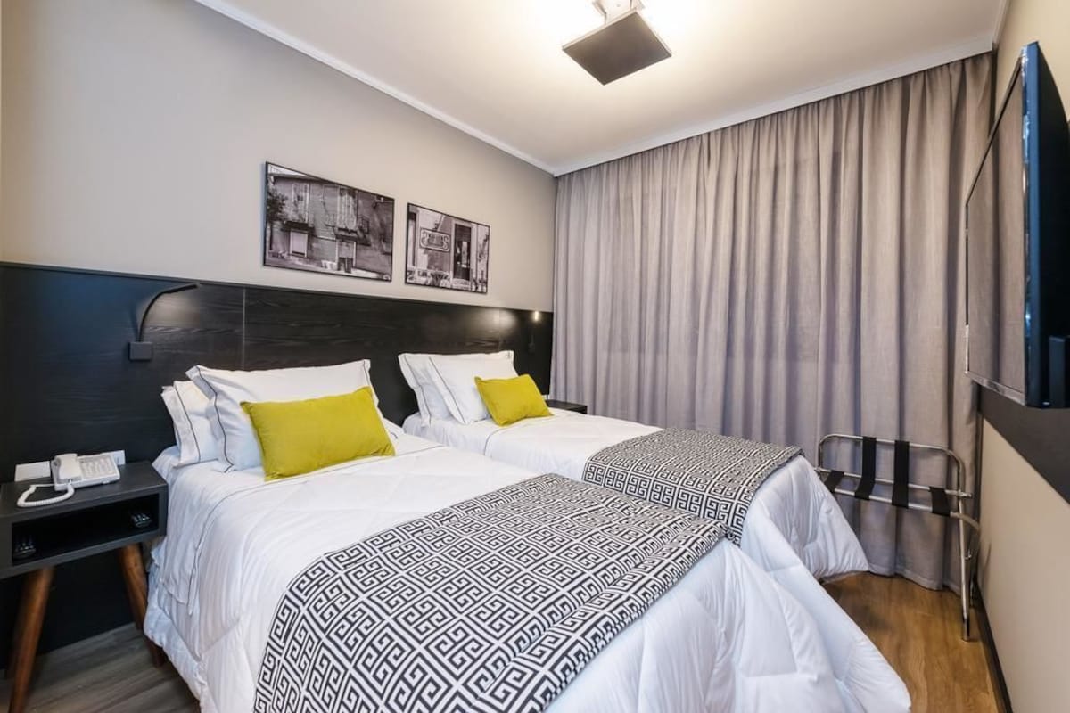 Ein Hotelzimmer mit zwei Betten, einem Schreibtisch mit Telefon und einem Fernseher.