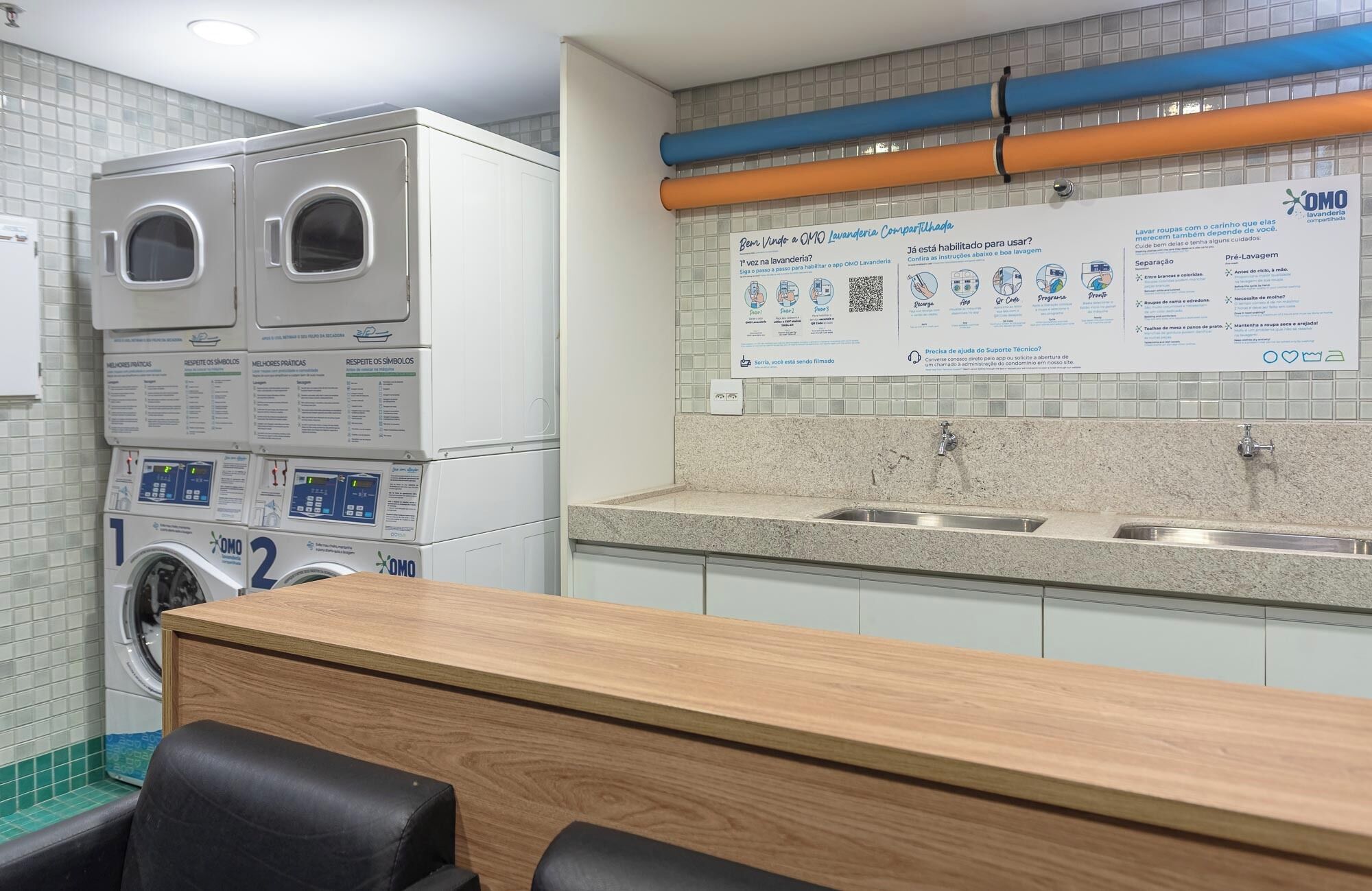 A laundry facility with two washing machines, a sink, and a wooden counter.