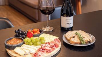 A charcuterie board with cheese, meats, fruits, and a bottle of wine on a table.
