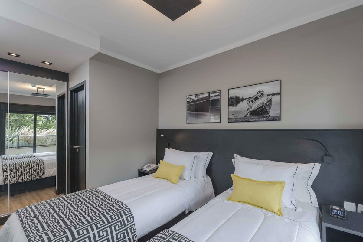 Ein modernes Hotelzimmer mit zwei Betten, einem großen Fenster und Kunstwerken an der Wand.