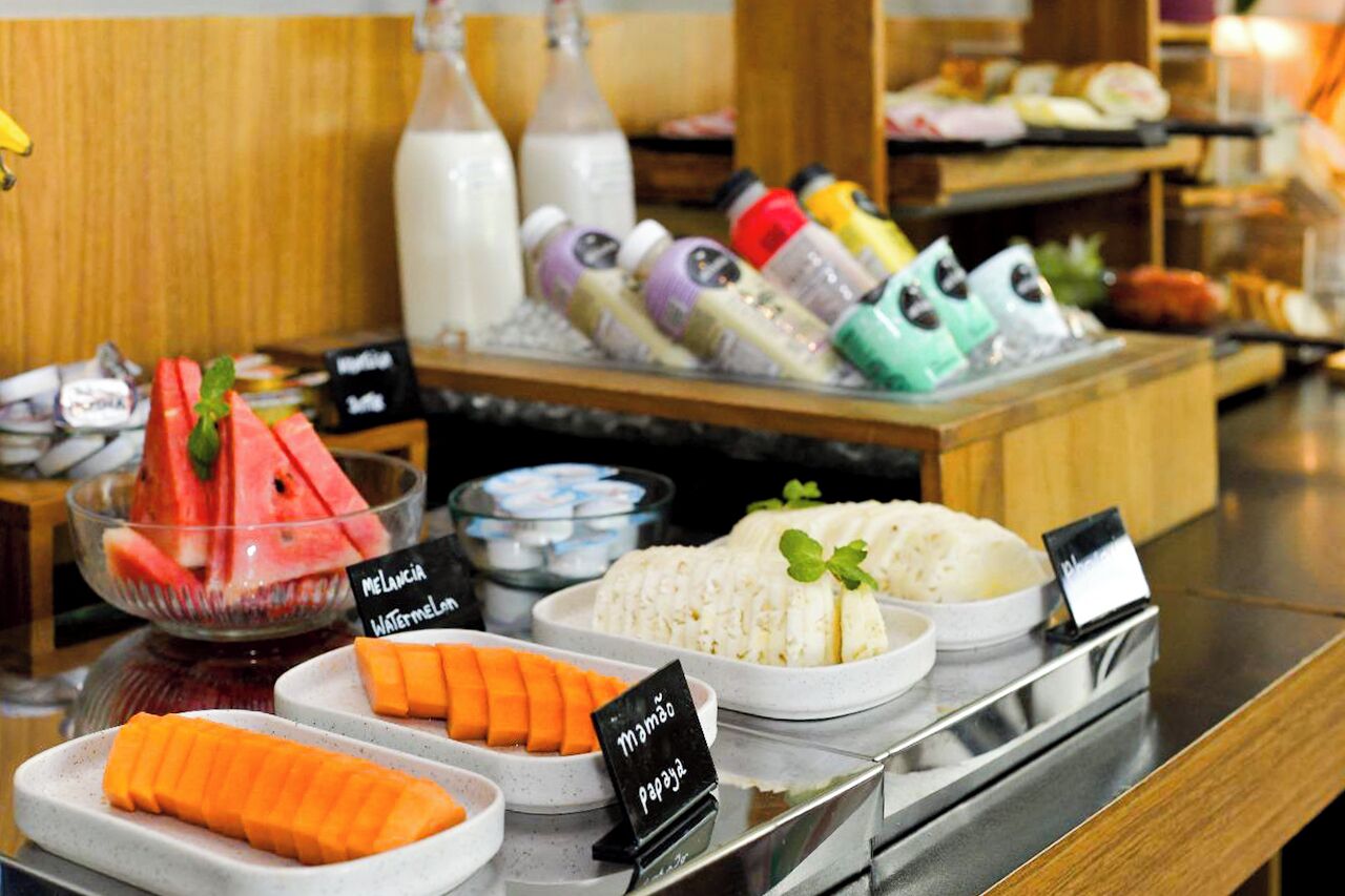 Buffet com diversos alimentos, incluindo melancia, mamão e arroz.