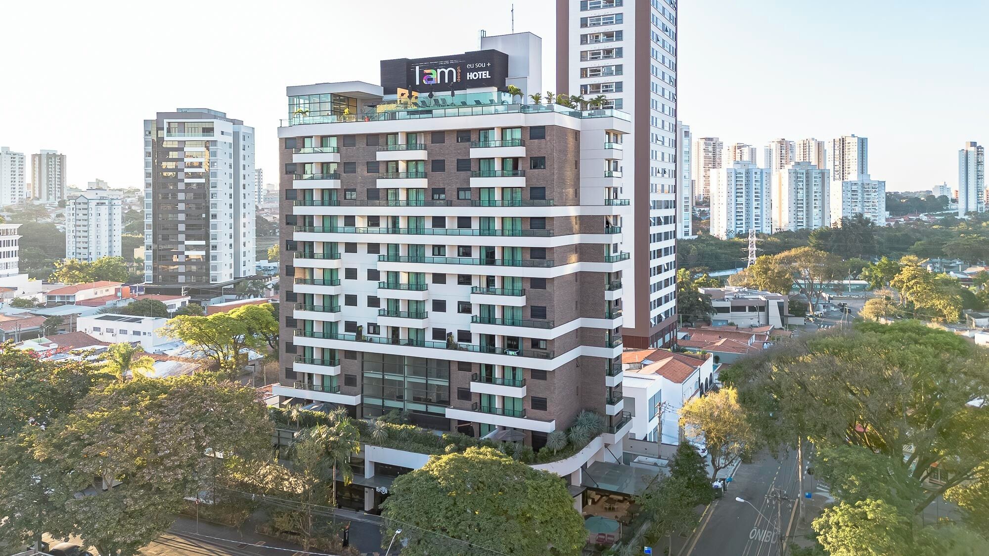 A multi-story hotel with a modern design, featuring balconies and a rooftop terrace.