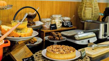 Buffet com diversos alimentos, incluindo bolo, pão e potes com patês.