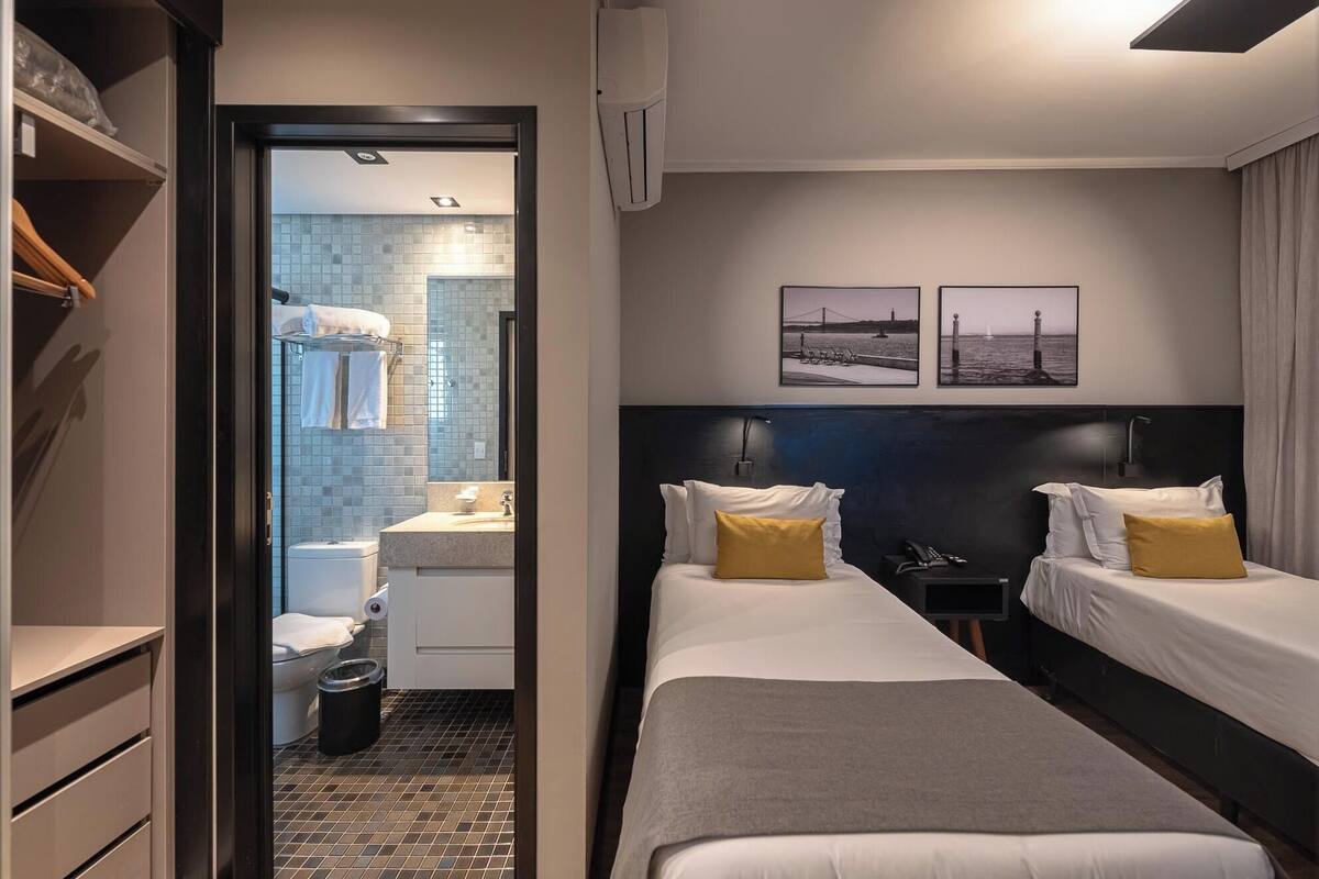 Habitación de hotel con dos camas, baño y vista al mar.