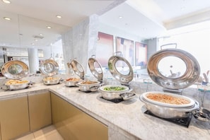 Buffet com várias estações de comida, cada uma com uma tampa.