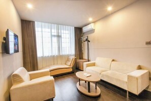 Een moderne hotelkamer met een bank, fauteuil en een klein, rond tafeltje.