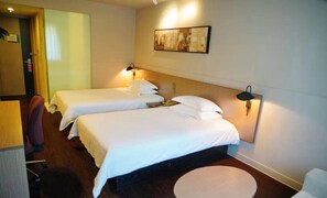 A hotel room with two beds, a desk, a chair, a round table, and a painting on the wall. - Jinjiang Inn Select Shanghai Expo Dezhou Road (Shanghai)