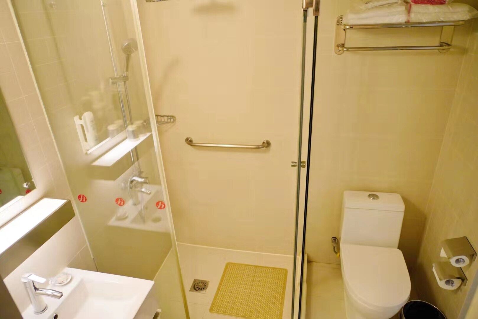 Un baño con ducha envuelta en vidrio, inodoro, lavabo y barra para toallas.