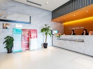 A reception desk with a sign reading 'JINJIANG INN,' a potted plant, and a large window. - Jinjiang Inn Shanghai Hongqiao Tianshan West Road (Shanghai)
