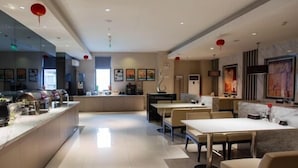 Un moderno vestíbulo de hotel con una zona de bar central, arreglos de asientos y obras de arte en las paredes.