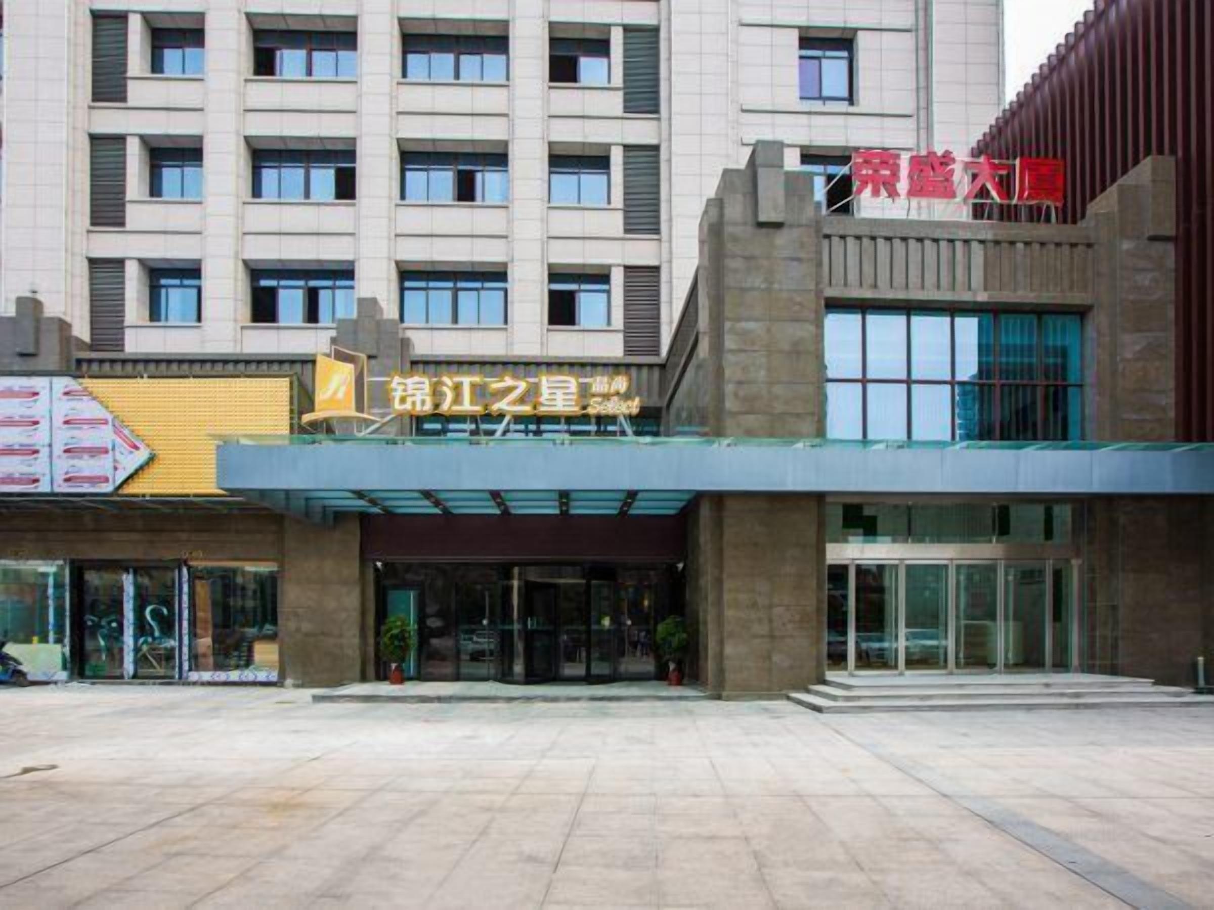 A hotel entrance with a modern design, featuring a prominent signboard and a glass facade.