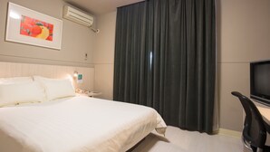 A hotel room with a bed, a desk with a chair, a television, and a large window with curtains. - Jinjiang Inn Select (Fanchang RT-Mart Business Square) (Wuhu)