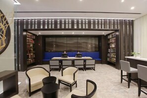 A modern library with bookshelves, a blue seating area, and a table. - Jinjiang Inn Select (Fanchang RT-Mart Business Square) (Wuhu)