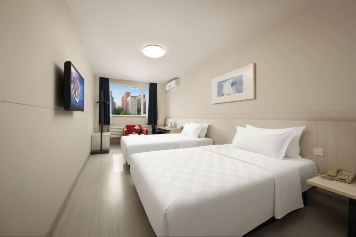 Ein Hotelzimmer mit zwei Betten, einem Fernseher, einem Schreibtisch und einem Fenster mit Blick.