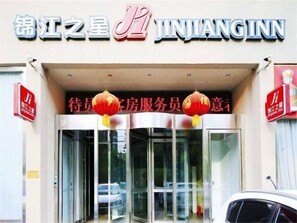 The entrance to Jinjiang Inn with a clear sign above the doors and two red lanterns hanging from the ceiling.