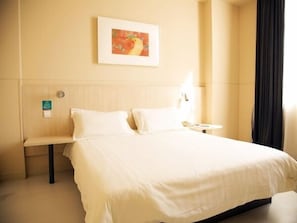 A hotel room with a large bed, a bedside table, a lamp, and a framed picture on the wall. - Jinjiang Inn (Harbin Shida Night Market Hexinglu Road Metro Station ) (Harbin)
