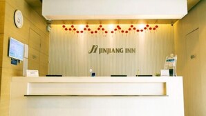 Un comptoir d’accueil avec une horloge et une enseigne indiquant « Jinjiang Inn ».