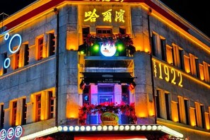 A building with illuminated signage, a prominent year '1922' on the facade, and a sign for 'ALL NATIONS FIRM' at the entrance. - Jinjiang Inn (Harbin Shida Night Market Hexinglu Road Metro Station ) (Harbin)