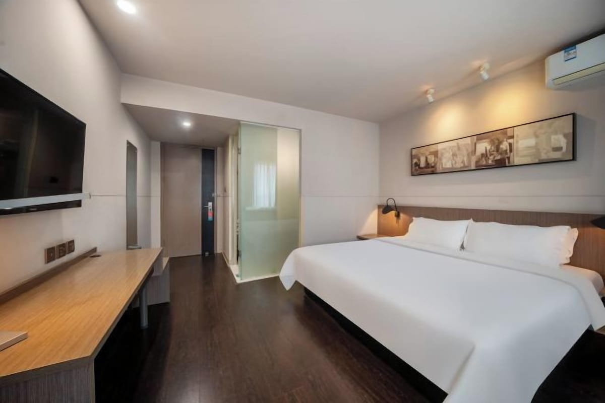 Une chambre d’hôtel moderne dotée d’un grand lit, d’un bureau, d’un téléviseur à écran plat et d’une œuvre d’art accrochée au mur.