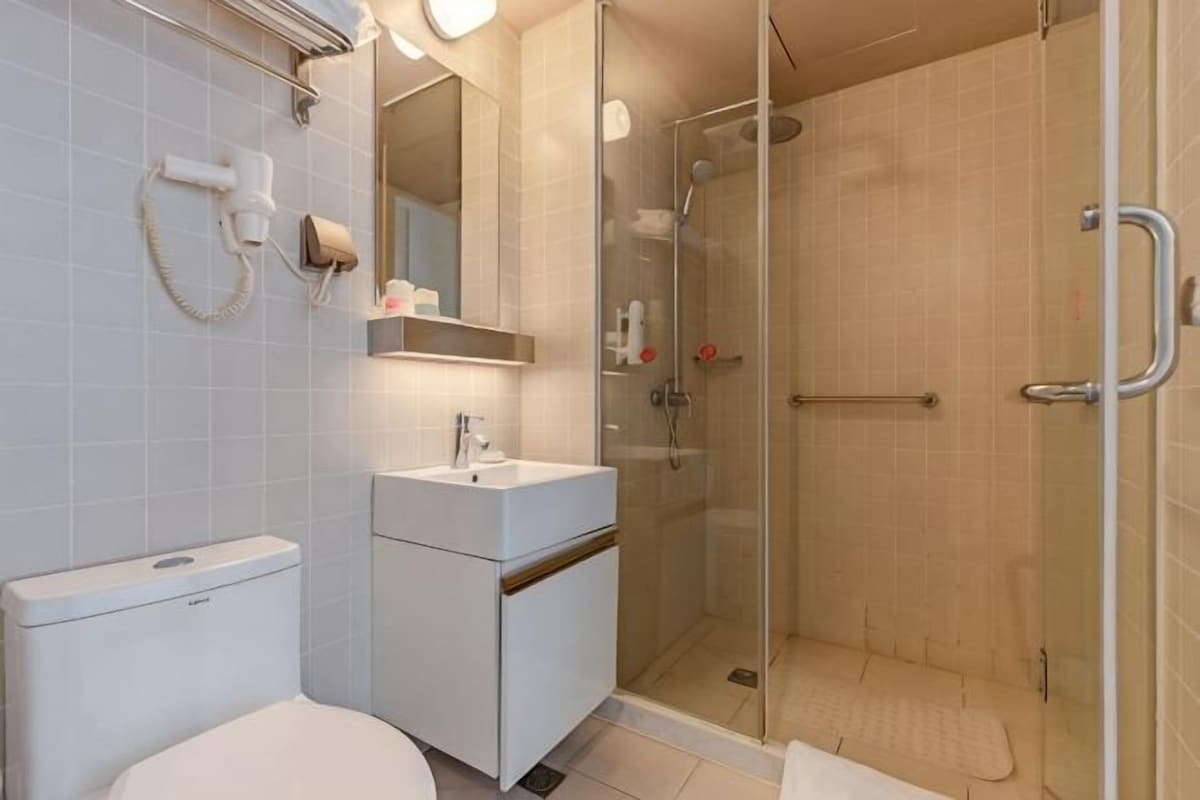 Une salle de bain moderne équipée de toilettes, d’un lavabo et d’une douche à parois de verre.
