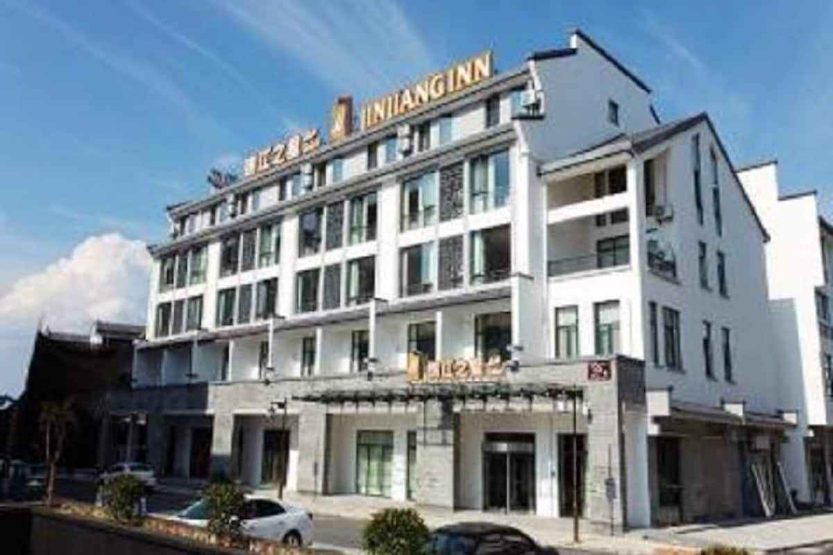 Ein mehrstöckiges Hotel mit auffälliger Beschilderung, einem Eingangsbereich im Erdgeschoss und einem sichtbaren Parkplatz.