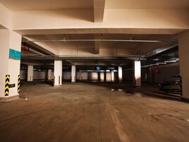 An underground parking garage with multiple levels, concrete pillars, and a few parked cars.