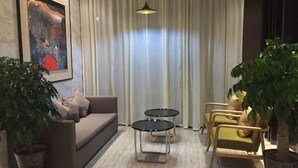 A modern living room with a sofa, two side tables, and chairs. There are two large potted plants and a framed artwork on the wall. - Jinjiang Inn Select (Hangzhou Binjiang University Town Puyan Metro Station) (Hangzhou)