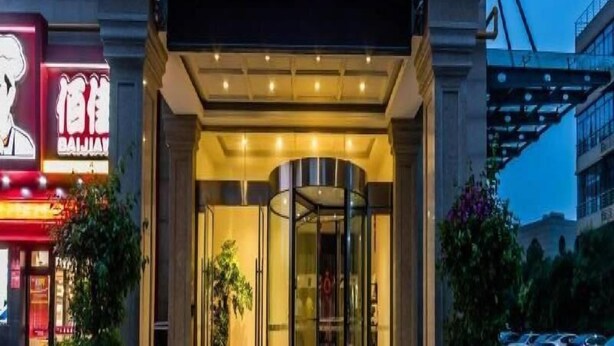A hotel entrance with a glass revolving door, a neon sign, and a modern building facade. - Jinjiang Inn Select (Hangzhou Binjiang University Town Puyan Metro Station) (Hangzhou)